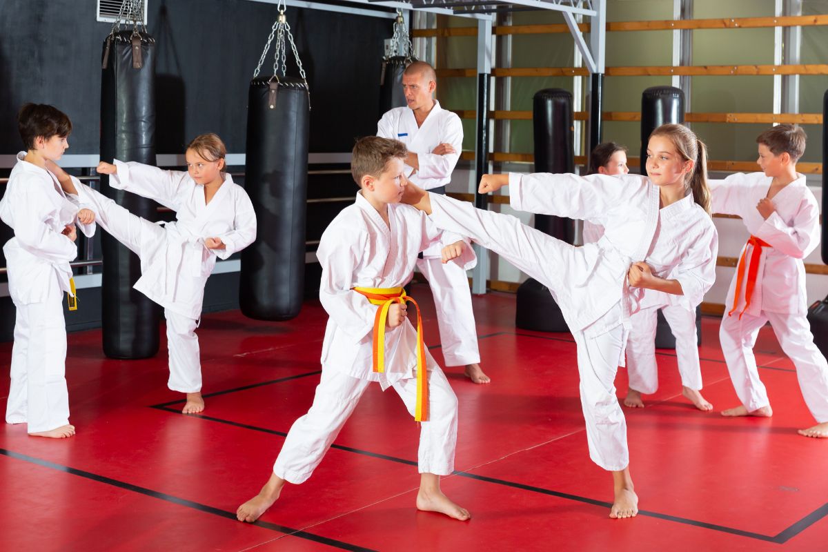 Children practicing karate techniques in white gis, guided by an instructor in a martial arts dojo