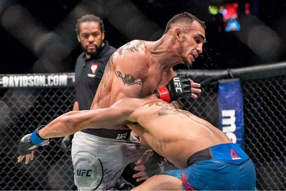 Two UFC fighters in the octagon, one delivering a powerful elbow strike while the other attempts to dodge